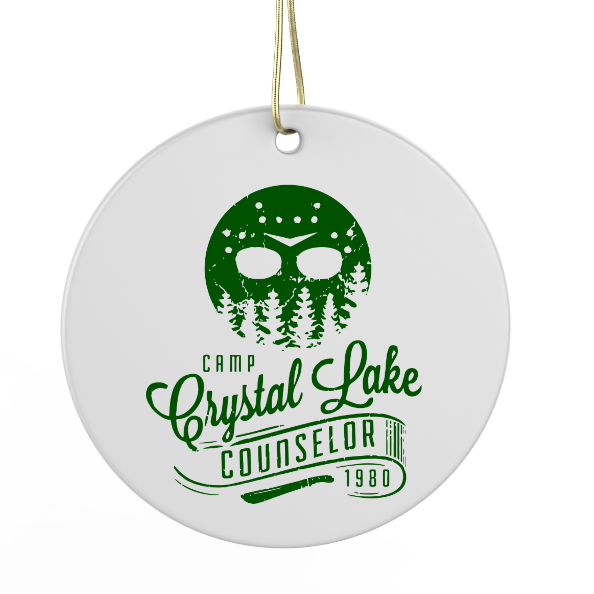 A white circular ornament with a green design featuring a stylized face and trees, along with the text "Camp Crystal Lake Counselor 1980".