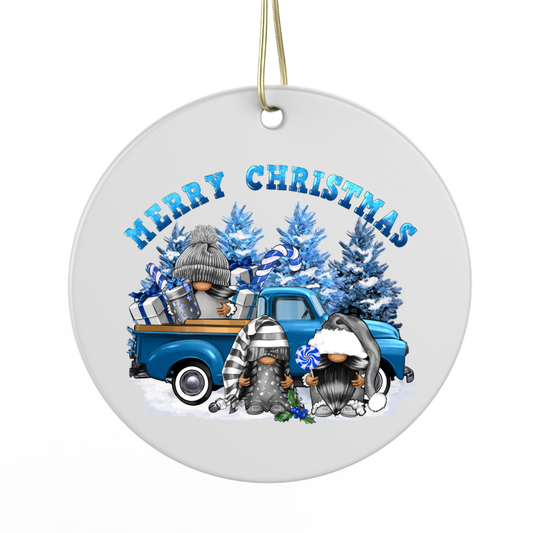 A round ornament featuring a blue truck with three gnomes sitting in the bed, surrounded by snow and Christmas trees.